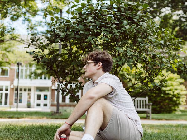 Student sits by himself and reflects outdoors
