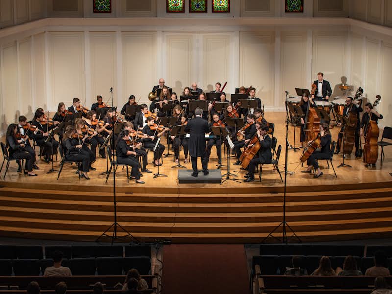 Musicians wearing black perform on a stage