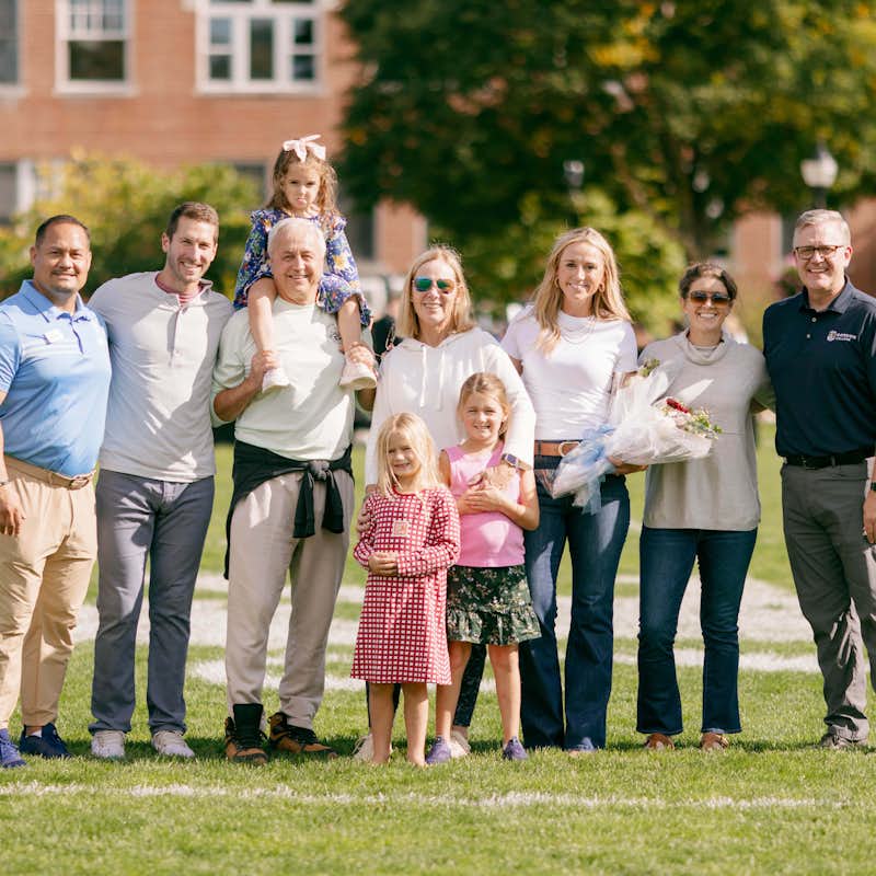 A family stands with the president and athletic director at homecoming