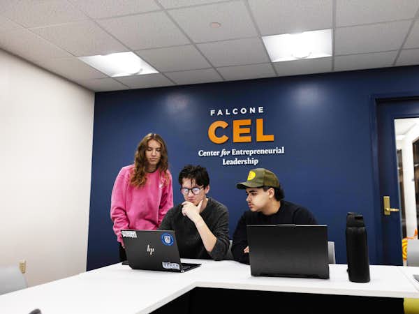 Three students review work on a computer in a classroom