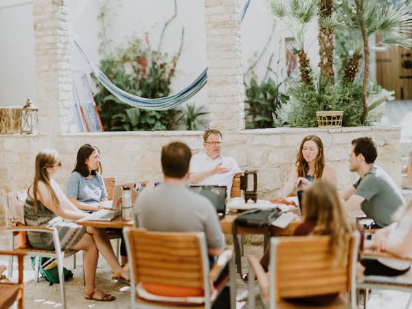 Students of Gordon College's Balkans Semester For the study of War and Peace converse at a table outdoors with their professor.
