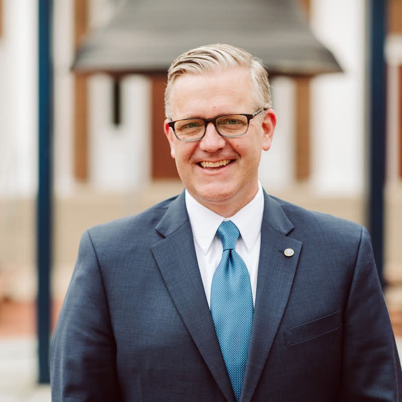 Portrait of President Michael Hammond standing outside in front of campus chapel