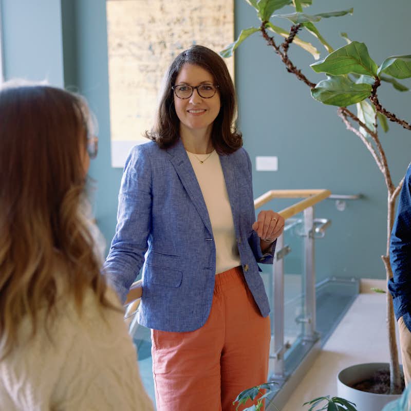 Students chat in hallway with professor Kristen Cooper