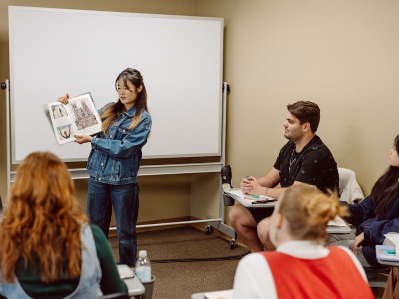 Gordon College student reads a picture book to a classroom of students