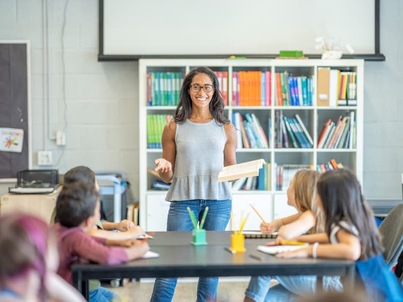 Female teacher stands in front of class of elementary students