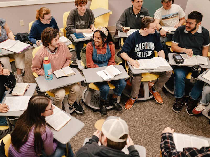 A classroom discussion between group of students at desks