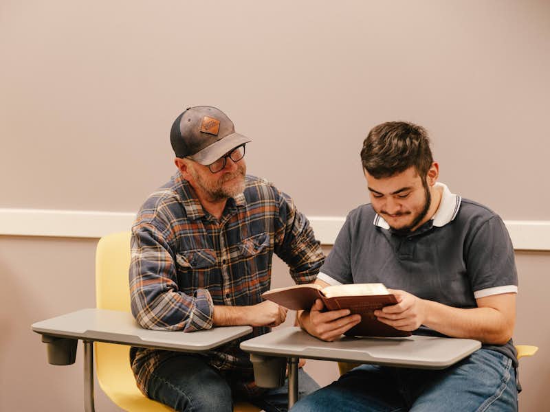 Professor Steve Hunt works with student studying scripture
