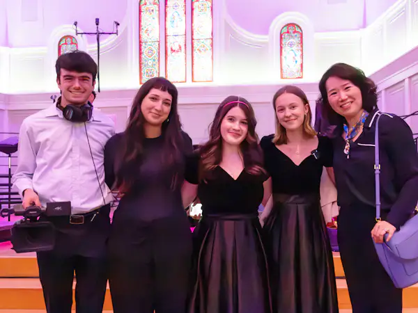 Film students and choir performers stand with their professor after an on-stage performance