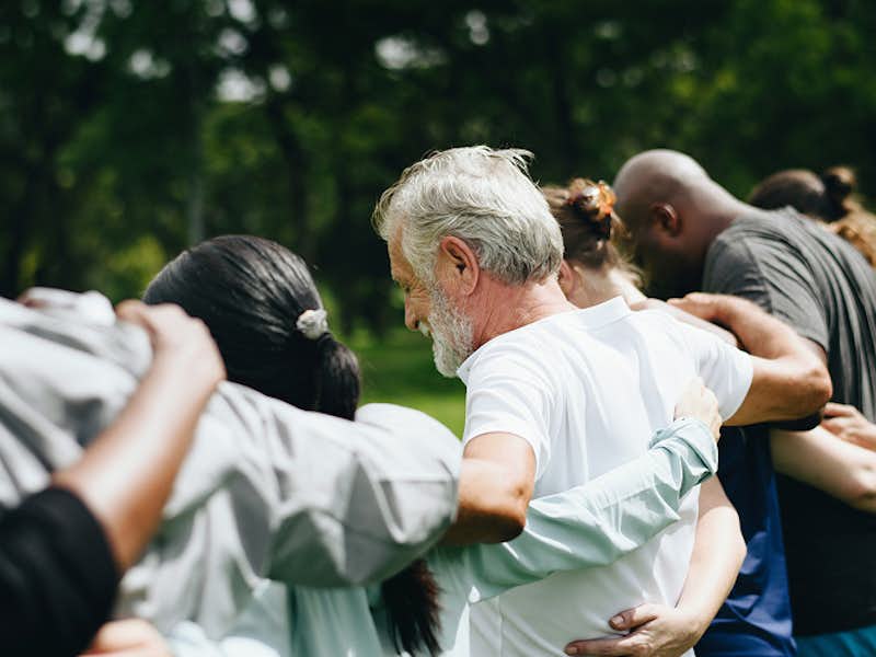 A group of people wrap their arms around each other