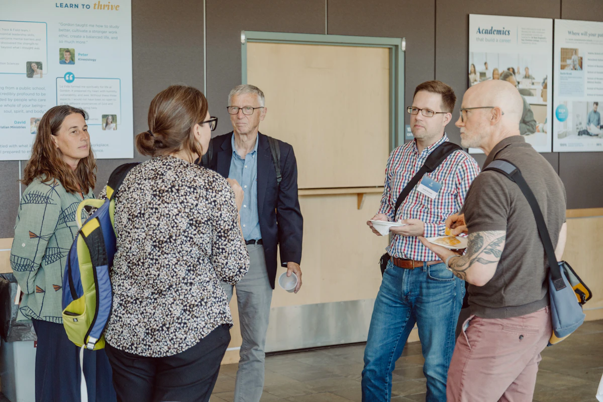 College faculty stand in a small circle and have a conversation with appetizers in hand.
