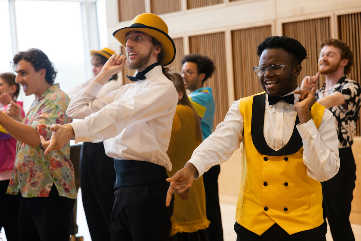 Students wear costumes and sing in a music hall performance.