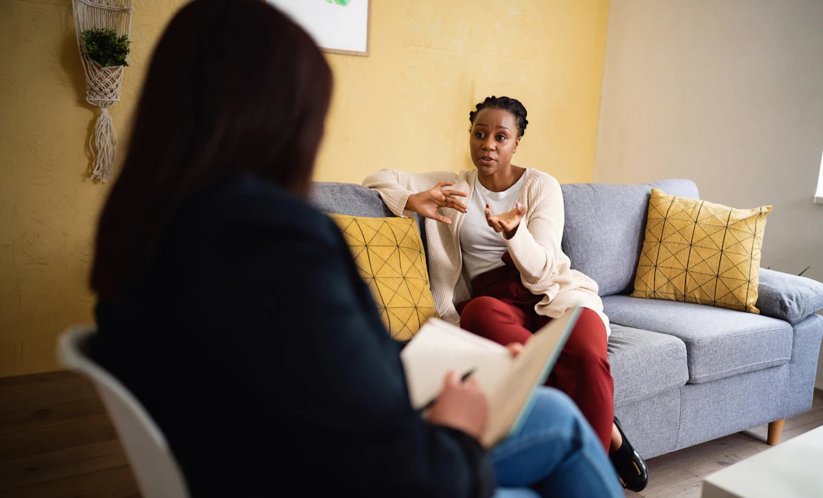 A client sits on a couch and speaks with her therapist