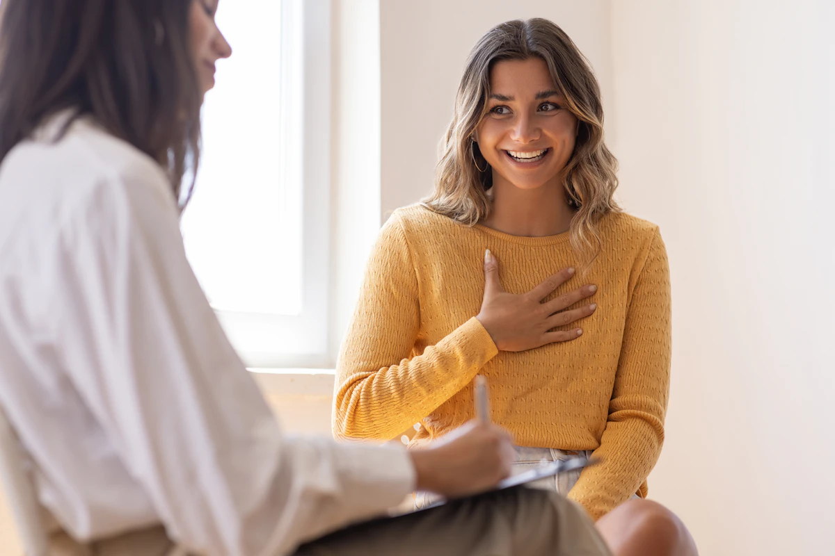 A client speaks to a therapist with her hand on her heart