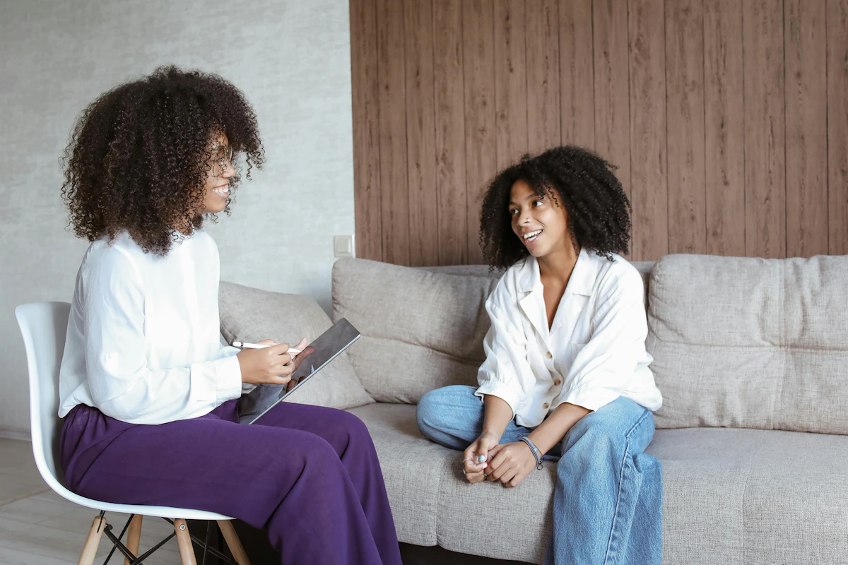A woman sits on a couch and talks to a counselor